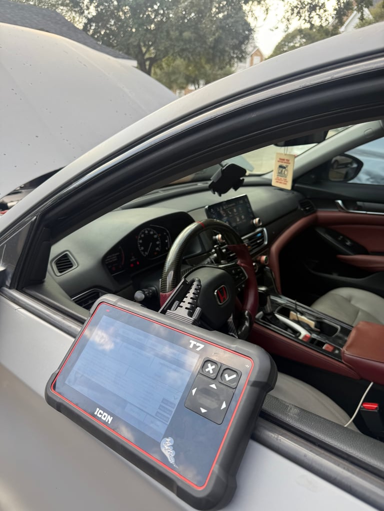 Diagnostic scanner device held near window of white BMW car with red leather interior and trees in background