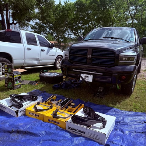 Outdoor display of jet skis and water sports equipment near two pickup trucks at what appears to be a recreational event or marina parking area