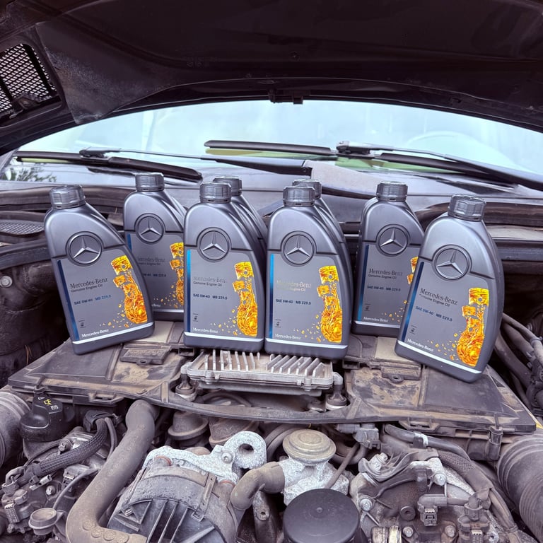 Six bottles of Mercedes engine oil with yellow labels displayed on an open car engine bay